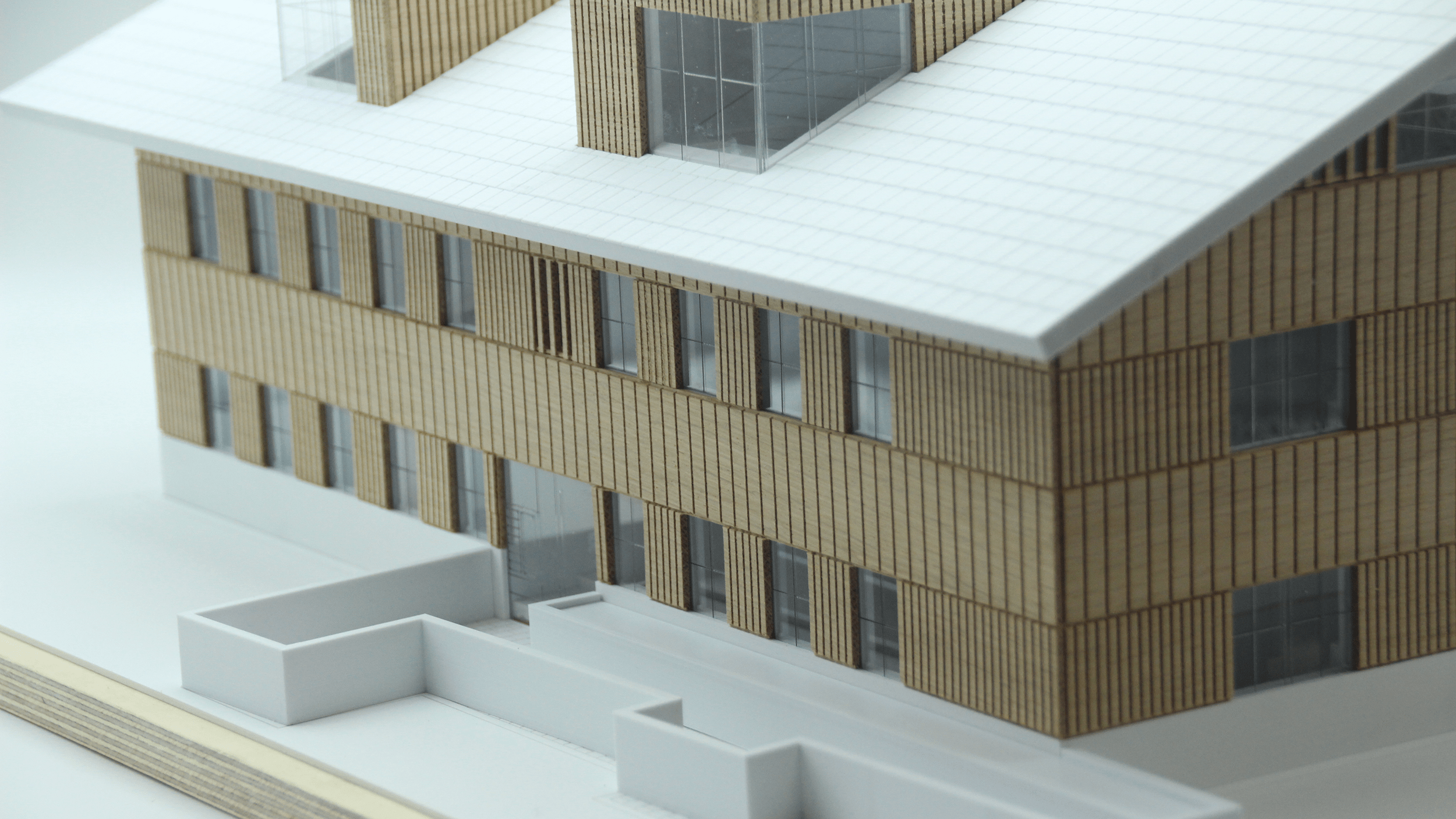 Detailansicht der Holzfassade des Architekturmodells mit Plexiglas-hinterlegten Fenstern und präzise gestalteten Dachgauben.
