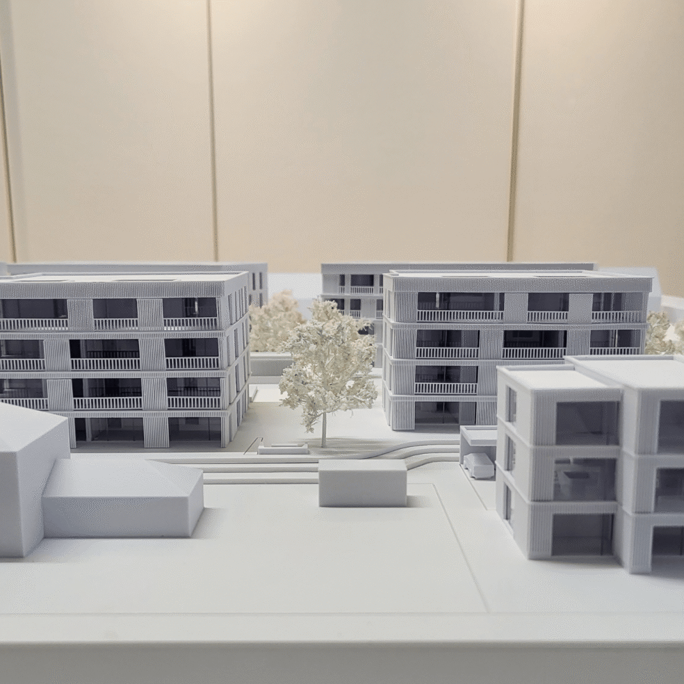 Schrägansicht des Architekturmodells ELLA Langenargen mit mehreren Wohngebäuden, Baumreihen und Erschließung.