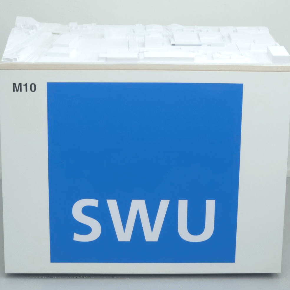 Umgebungsmodell des SWU-Standorts auf einem weißen Ausstellungssockel mit blauem SWU-Logo.